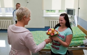 Presenting baby shoes to children born on 20.08.09. Evelin Ilves gives flowers to Katri Laas, mother of Romet who was born on August 20